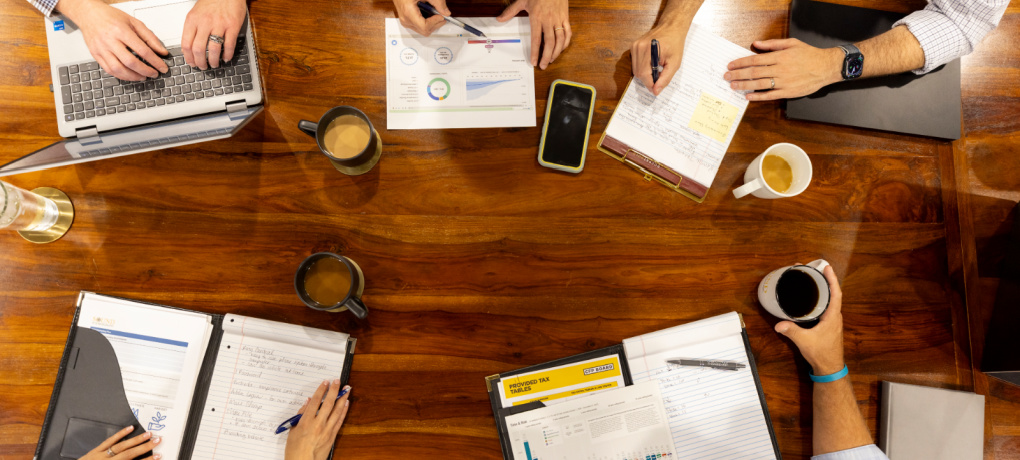 An above shot of hands busy working on financial planning documents.