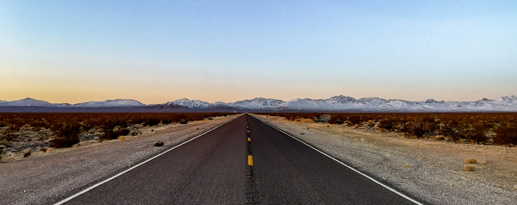 Driving down the open road with a blue sky and mountains on the horizon