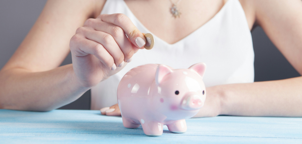 Image of a woman adding money to a piggy bank for a child.