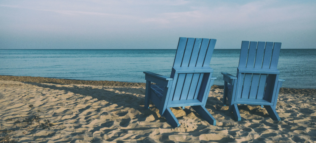 An image of two blue beach chairs looking over the ocean in retirement