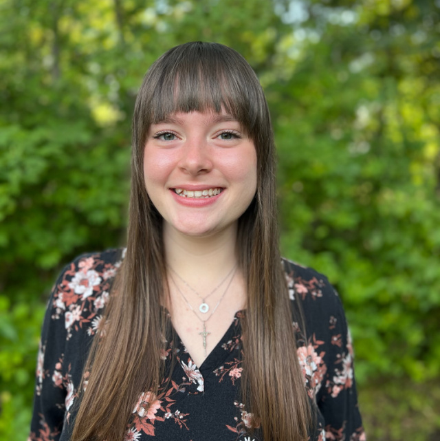 Headshot of Rachael Holguin in front of greenery.